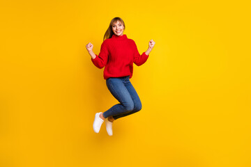 Sticker - Full size photo of blond optimistic lady jump hands fists wear red sweater jeans sneakers isolated on bright yellow color background