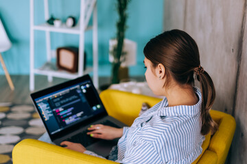 Young woman mobile developer with laptop, writes program code on a computer, programmer work in modern office.
