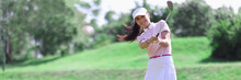 Woman Golfer With Golf Club In Hand And Flying Ball After Hitting. Sports And Golf Concept