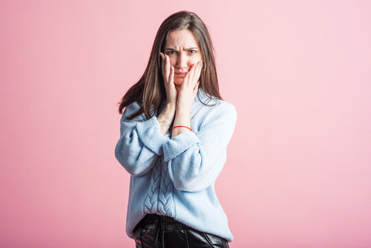 Scared brunette girl in studio on pink background