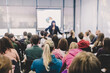 © kasto - Speaker giving presentation in lecture hall at university. Participants listening to lecture and making notes.