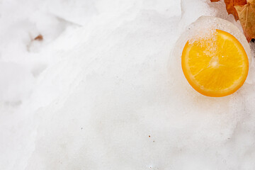 Sliced orange on a snow background. Spring concept, vitamins. There is a place for text