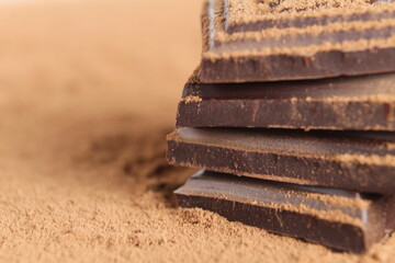 Wall Mural - pieces of chocolate lie tower on top of each other on a cocoa on a white background with space for text copyspace