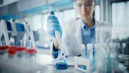 Wall Mural - medical research laboratory: portrait of a beautiful female scientist in goggles using micro pipette