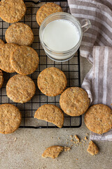 Wall Mural - Healthy oatmeal cookies with cereals, seeds and nuts with a cup of milk on concrete background. Diet vegan cookies. Top view.