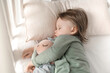 © Alexandr - baby sleeps in a crib, in the rays of sunlight, hugging a toy