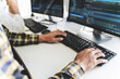 © mojo_cp - programmer writing program code with two monitors and working on a new software or hacker programming developing software applications in the office.