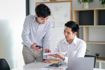 Wall Mural - asian man designers are looking for ideas to make a website ui ux mobile phone application at the of