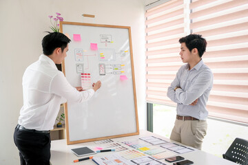 Wall Mural - asian man designers are looking for ideas to make a website ui ux mobile phone application at the of