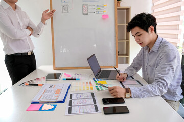 Wall Mural - asian man designers are looking for ideas to make a website ui ux mobile phone application at the of