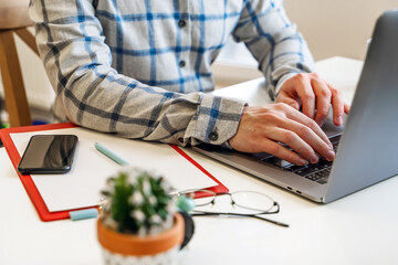 Wall Mural - a man in a shirt sits in a modern office and uses a laptop to work in business or programming, appli