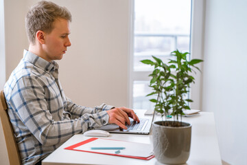 Wall Mural - handsome man working using computer laptop and drinking a mug of coffee with thinking serious face i