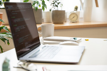 Wall Mural - The laptop on a white desk in a bright office, the code on the screen