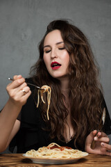 A beautiful young woman eats Italian spaghetti pasta. The brunette girl have lunch in a cafe