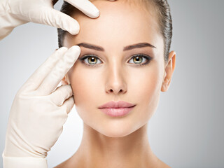 face skin check before plastic surgery. beautician touching woman face.