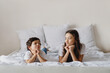 © Olena Bloshchynska - Little boy and his sister looking at each other while lying on a bed.