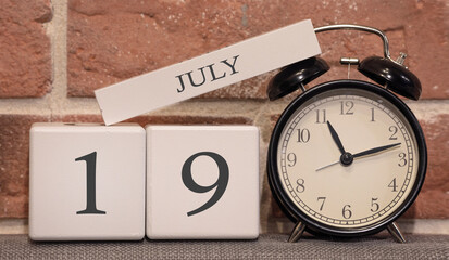 Wall Mural - Important date, July 19, summer season. Calendar made of wood on a background of a brick wall. Retro alarm clock as a time management concept.