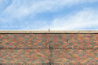 Top of an Exterior Brick Wall under a Cloudy Blue Sky