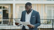 © stockbusters - Afro businessman examining documents outdoor. Focused african man looking papers