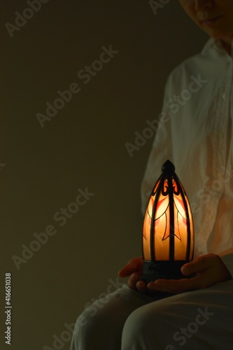“art deco” lamp. made in France. \
Asian woman holding candle shines with warm light . \
\
dim lighting room soft focus image.