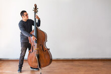 Professional Double Bass Player. Photo Shooting In Studio. White Background