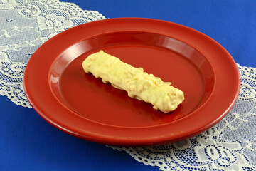 Sticker - White chocolate and peanut wafer candy bar on red snack plate on lace table runner on blue tablecloth