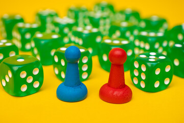 Two red and blue game chips and playing green cubes laid on a yellow background: entertainment, games at home for the whole family, table board games concept with space for text 