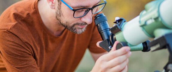 Wall Mural - amateur astronomer looking at the sky with a telescope.