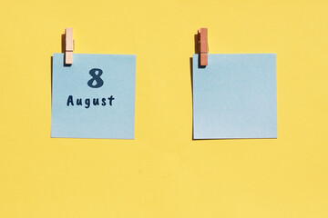 August 8. 8th day of the month, calendar date. Two blue sheets for writing on a yellow background. Top view, copy space. Summer month, day of the year concept