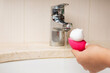 Woman cleansing makeup sponge with foam over sink