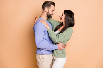 Poster - Photo of young happy positive good mood smiling couple husband wife embrace each other isolated on beige color background