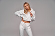 © kiuikson - Beautiful sexy blonde woman wear of white set of tracksuit isolated on gray background