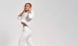 © kiuikson - Beautiful blonde woman wear of white tracksuit isolated on gray background