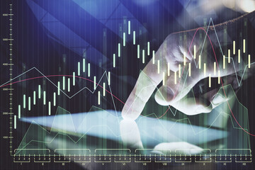 Double exposure of man's hands holding and using a digital device and forex graph drawing. Financial market concept.