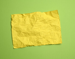 Wall Mural - blank crumpled yellow sheet of paper on a green background