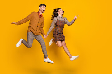 Poster - Full size profile side photo of excited couple point go empty space jump isolated on yellow color background