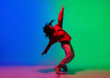 Inspiration. Stylish sportive girl dancing hip-hop in stylish clothes on colorful background at dance hall in neon light. Youth culture, movement, style and fashion, action. Fashionable bright