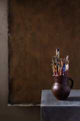 Poster - Paint brush in clay jug or pot on abstract background texture. Art painter concept