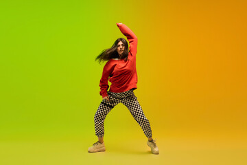 Wall Mural - Dynamic. Stylish sportive girl dancing hip-hop in stylish clothes on colorful background at dance hall in neon light. Youth culture, movement, style and fashion, action. Fashionable bright portrait.
