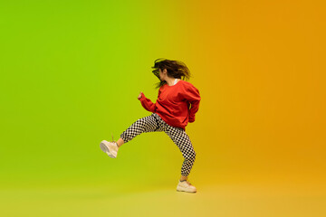 Wall Mural - Action. Stylish sportive girl dancing hip-hop in stylish clothes on colorful background at dance hall in neon light. Youth culture, movement, style and fashion, action. Fashionable bright portrait.
