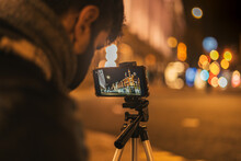 Young Man Taking A Picture In The Street At Night Time.