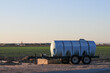 A fertilizer tank trailer at a farm at a farm field in Arizona, with crops growing in the backdrop