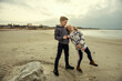 Two happy teenager children siblings walking on Baltic sea beach in spring