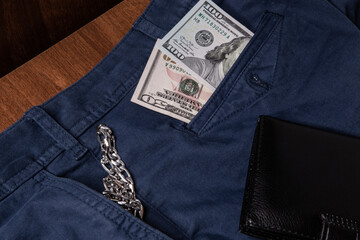 dollars, silver chain in jeans on wooden background