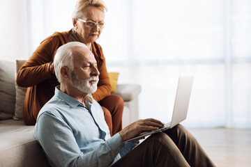 Wall Mural - Senior couple surfing the Internet on their laptop at home