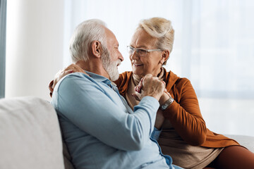 Wall Mural - Happy mature couple sitting on sofa and communicating