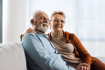 Wall Mural - Happy mature couple relaxing together on a sofa at home