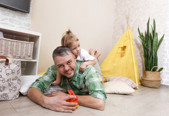 Wall Mural - A happy and loving father plays at home with his daughter. Father's Day concept.