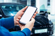© vadish - White screen on a smartphone in the hands of a man against the backdrop of a car. Template for a mobile application.