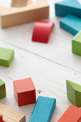 Closeup of colorful wooden toy blocks on white background wooden table. The child plays with colored cubes.